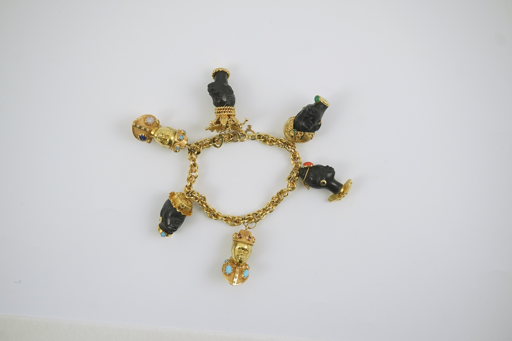 A late 20th century Italian 18k gold charm bracelet, hung with six assorted Italian 18k gold and gem set mounted blackamoor busts, together with a matching brooch